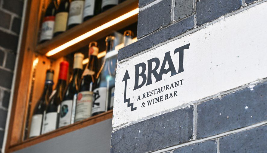 The Brat restaurant sign beside a wine shelf